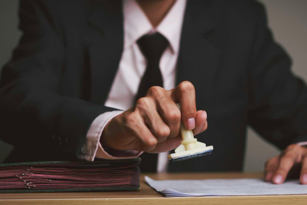 A professional man in a suit confidently holds a piece of paper, exuding a sense of authority and importance.